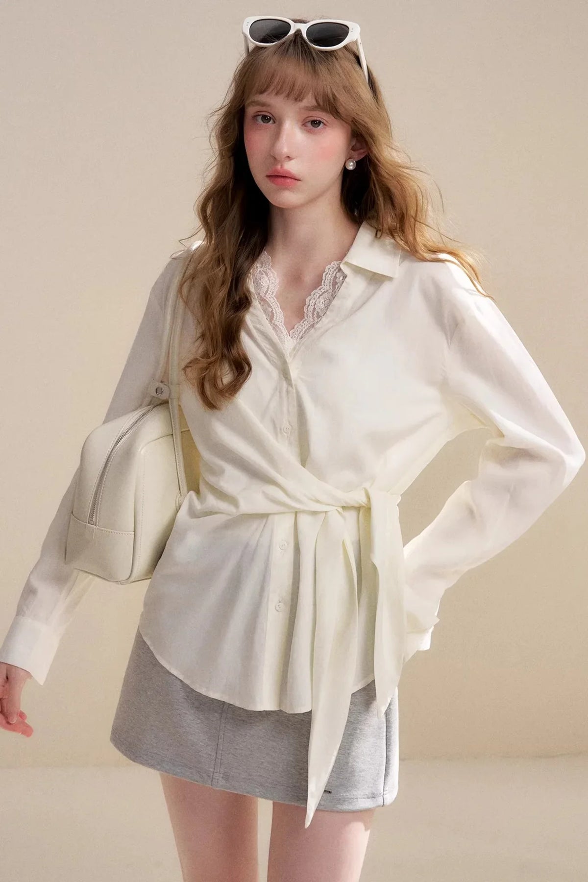 A light apricot long-sleeve blouse with delicate lace trim and a tie-waist detail.