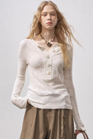 A model wearing an apricot-colored knit sweater with a Henry collar and sequin details.