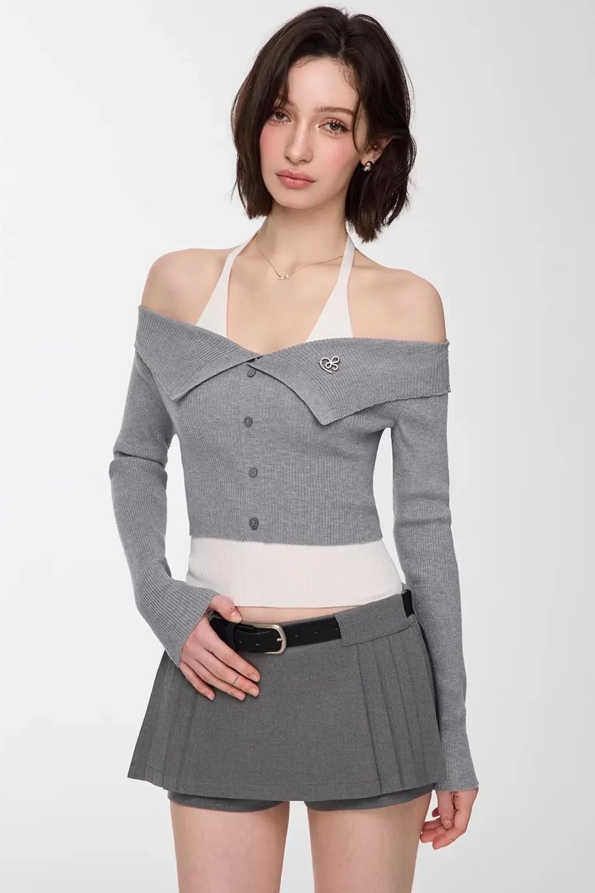 A model wearing a gray and white off-shoulder knit top.