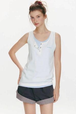 A woman wearing a white and gray color-blocked sleeveless vest with snap-button details.