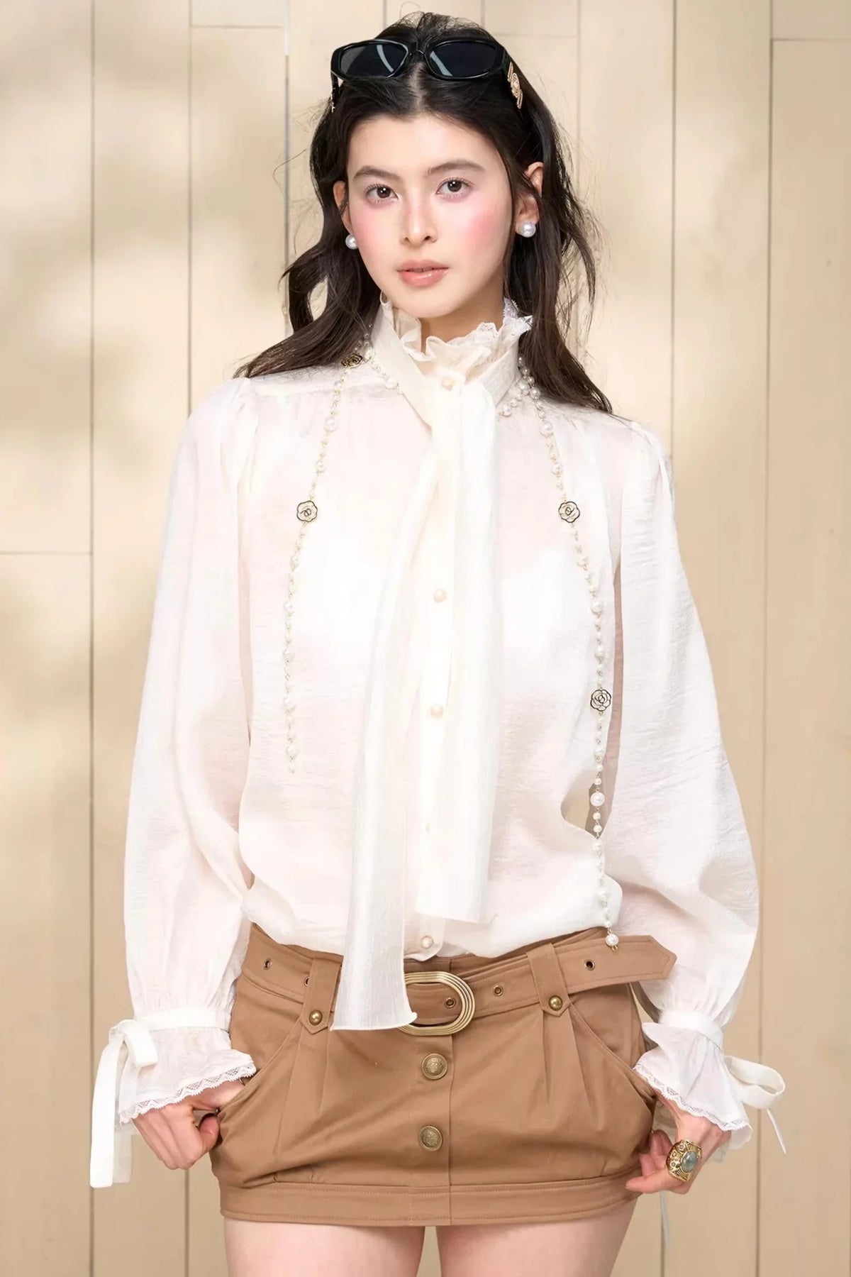 A white chiffon shirt with elegant tassel and ribbon details.