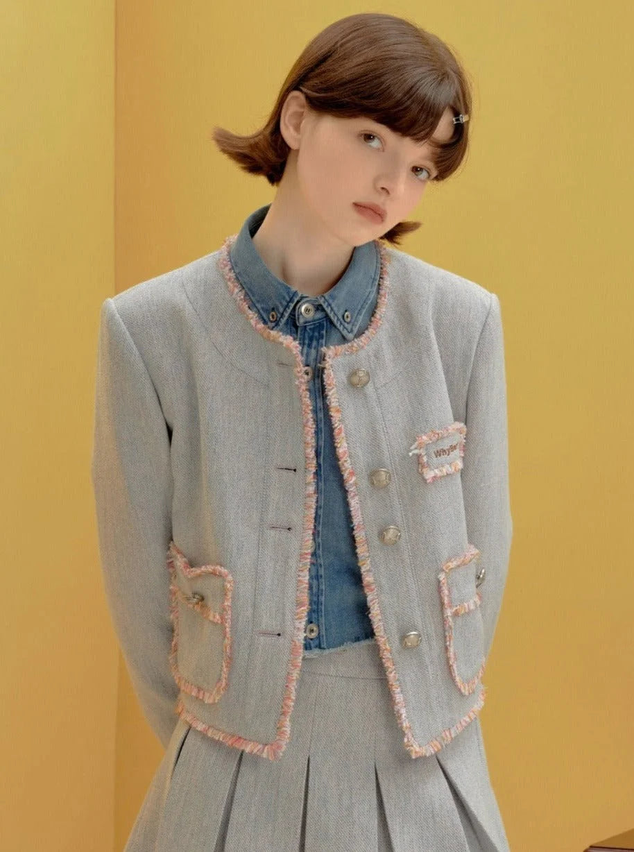 A woman wearing a light blue cropped jacket with fringe trim and matching skirt.