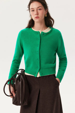 A woman wearing a vibrant green button-down knit cardigan.