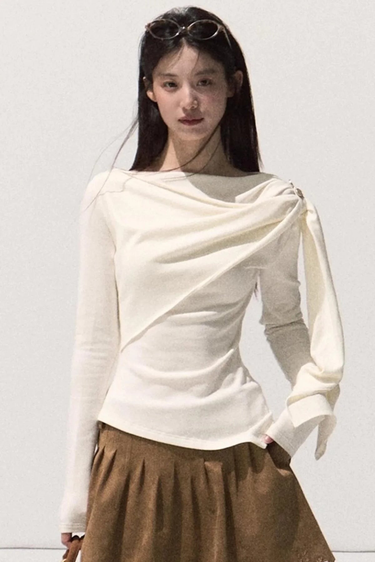 A white wrap-around knit sweater with elegant draping.
